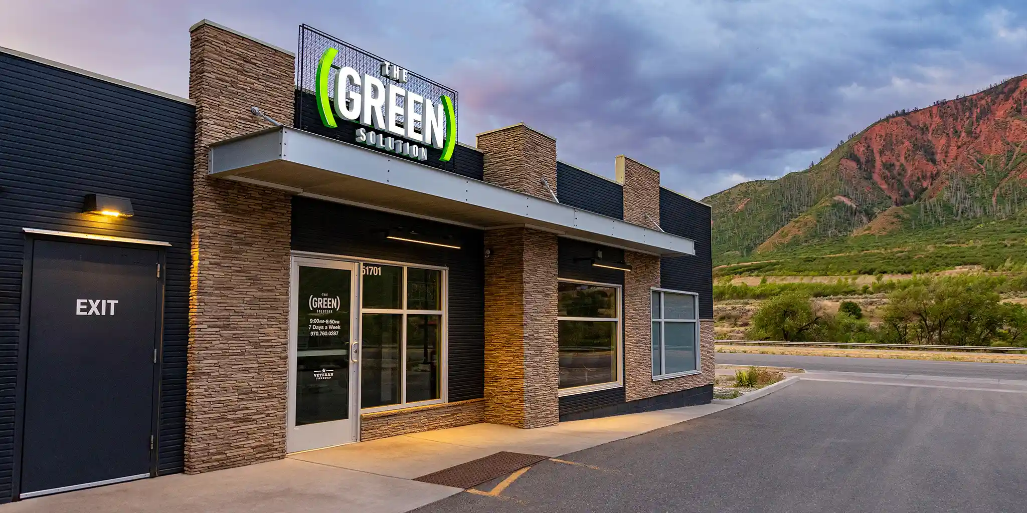 A Green Solution dispensary at dusk, Colorado hills behind it